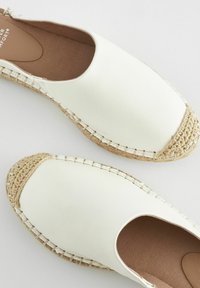 Vita läder espadriller slip-on med rund tå, flätade juteaccenter och en strukturerad tan inlägg. Slät yta med sömmade kanter.