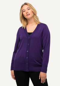 Lila cardigan i mjukt stickat tyg. Har en djup V-hals, långa �ärmar och sex matchande knappar fram. Ribbstickade mudd och nederkant.
