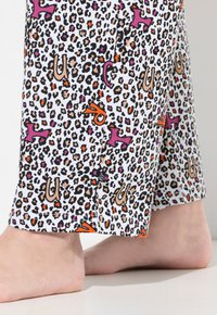 Leopardenmuster-Pyjama-Hosen in Weiß mit orangefarbenen, pinken und schwarzen Akzenten; Baumwollmaterial mit entspanntem Schnitt und sichtbaren Nähdetails.