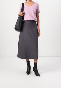 Rosa v-ringad t-shirt, grå midikjol, svart handväska och svarta ankelskor. Slät tygkvalitet, avslappnad passform och skräddarsydd design.