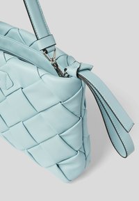 Jasnoniebieska torebka ze skóry pleciona, wyposażona w zamek błyskawiczny, regulowany pasek oraz miękką fakturę z wyraźną, strukturą.