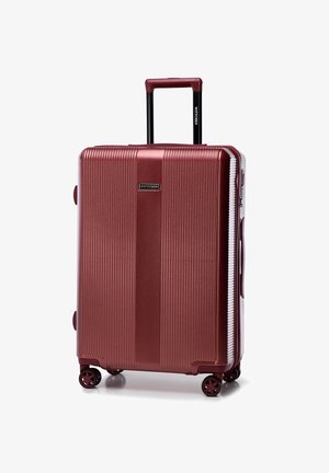 Valise rigide rouge avec des rainures verticales, poignée rétractable et quatre roues. Présente un logo de marque sur le devant et des poignées latérales.