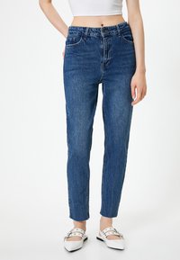Jean en denim bleu avec une coupe droite, taille haute et délavage léger. Dispose de passants de ceinture, de poches avant et d'un ourlet avec bords bruts.