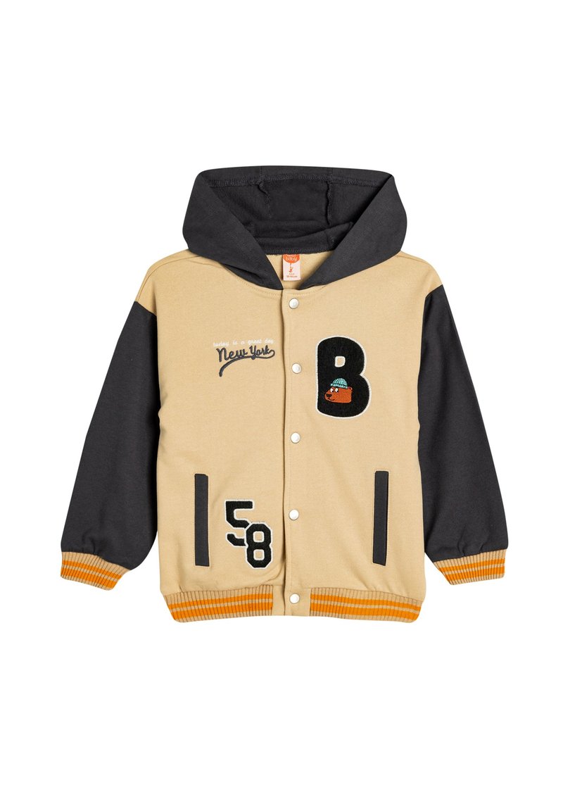 Beige og sort hættejakke med trykknapper. Har broderet tekst, numre og et grafik på forsiden. Ribbede orange manchetter.