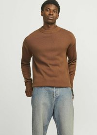 Brauner Baumwollstrickpullover mit gerippter Textur und Rundhalsausschnitt, kombiniert mit hellblauen Jeans.