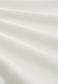 Mehka bela tkanina z subtilnimi gubami in gladko teksturo, prikazana v bližnjem posnetku.