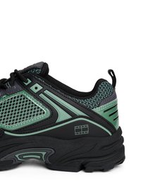 Baskets de sport noires et vertes avec des panneaux en mesh, des accents texturés et un col rembourré. Présente un détail de logo et une conception de semelle supportive.