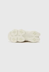 Semelle de chaussure en caoutchouc texturé, de couleur crème clair, avec des motifs en forme de losange et des détails de rembourrage prononcés.