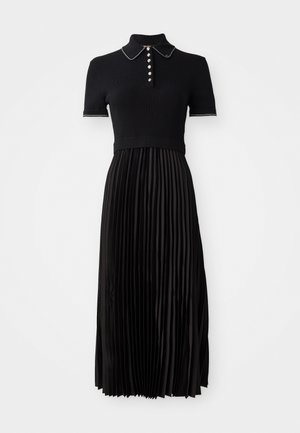 Black dress with a ribbed, short-sleeve top and pleated satin skirt. Features a collared neck and decorative buttons on the front.
