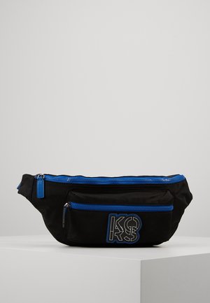 Sac banane noir avec deux compartiments zippés bleus et un logo "KORS" bleu et blanc sur la poche avant.