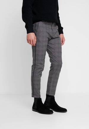 Pantaloni grigi a quadri con una vestibilità slim, caratterizzati da un tessuto testurizzato, gamba affusolata e dettagli con strisce laterali, abbinati a stivali alla caviglia in suede neri.