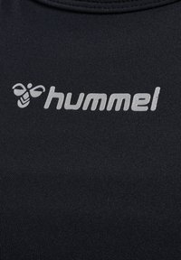 Svart sportstopp i fukttransporterande tyg med en silverfärgad "hummel"-logotyp och bi-emblem. Slät textur och figurnära design.
