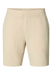 Shorts en tissu beige texturé avec taille élastique et détails subtils sur la couture avant.