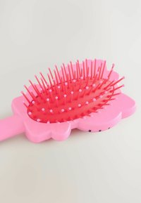 Rosa hårborste formad som en blomma med en texturerad röd bas, med flexibla plastborstar och ett slätt handtag.
