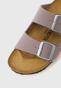 Lila növényi alapú bőrből készült szandál, két állítható pánttal ezüst fém csatokkal és párnázott parafa talpbéléssel. Gumi talp.