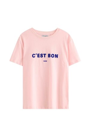 Maglietta a maniche corte rosa chiaro con testo blu navy "C'EST BON" e più piccolo "PARIS" stampato sotto sul davanti.
