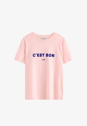 Maglietta a maniche corte rosa chiaro con testo blu navy "C'EST BON" e più piccolo "PARIS" stampato sotto sul davanti.