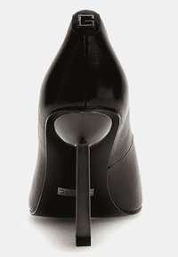 Chaussure à talon aigu noir avec un bout pointu, un talon stiletto fin, et un petit logo carré à l'arrière de la languette du talon.