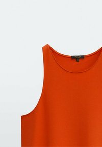 Débardeur orange avec un col rond et un tissu lisse et léger. Le design est sans manches et offre une coupe décontractée.