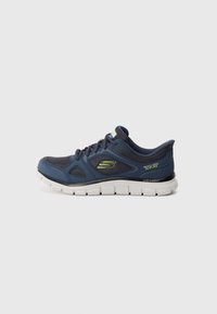 Navy blue Skechers slip-on sneaker with lightweight white sole and lime green logo on side, viewed from the outer side.