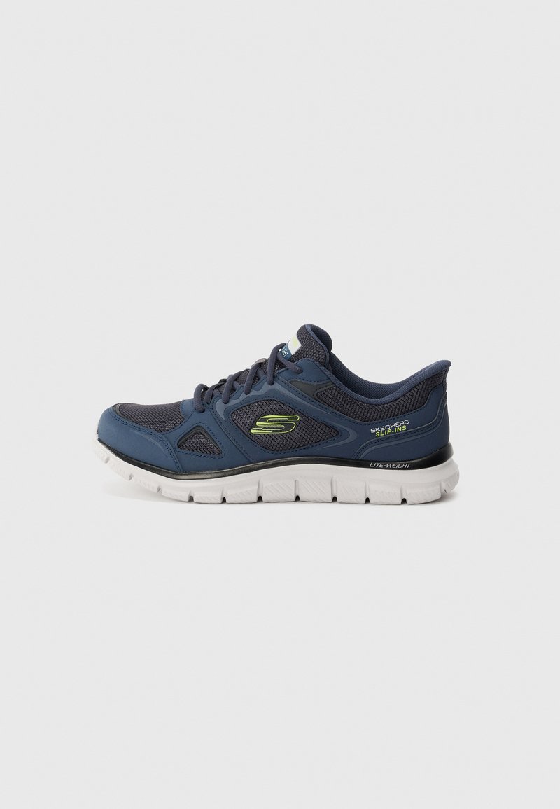 Navy blue Skechers slip-on sneaker with lightweight white sole and lime green logo on side, viewed from the outer side.