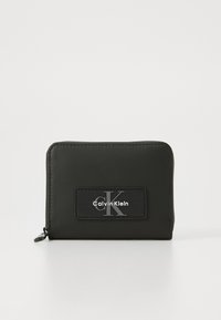 Zwarte portefeuille met rits, gemaakt van glad materiaal, met een verhoogd zwart patch met het "Calvin Klein" logo en een zilveren "cK" accent.