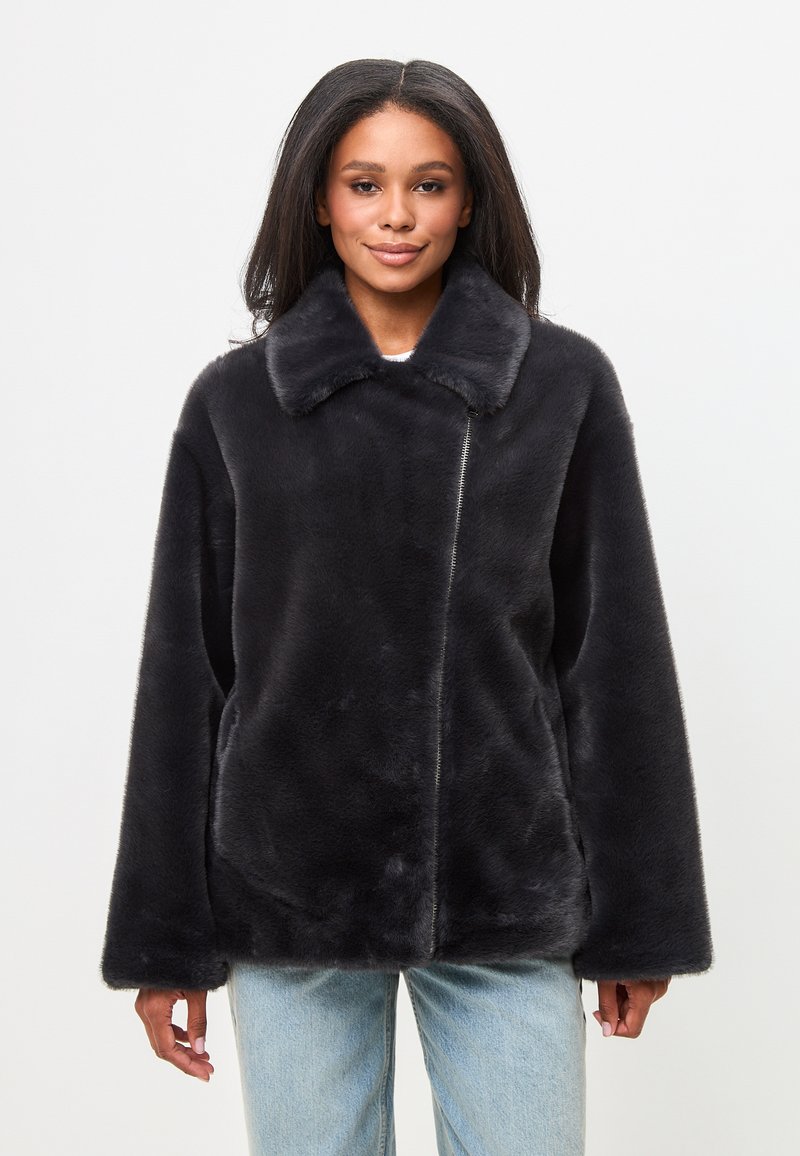 Jachetă neagră din blană artificială cu guler, croi oversized și buzunare laterale. Textură moale și un design curat, minimalist.