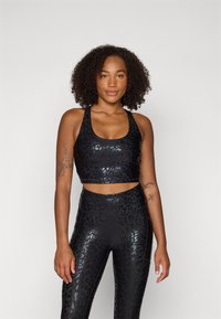 Crni sportski crop top s dezenom leopard print i sjajnom teksturom, u kombinaciji s odgovarajućim tajicama visokog struka u istom uzorku i završnoj obradi.