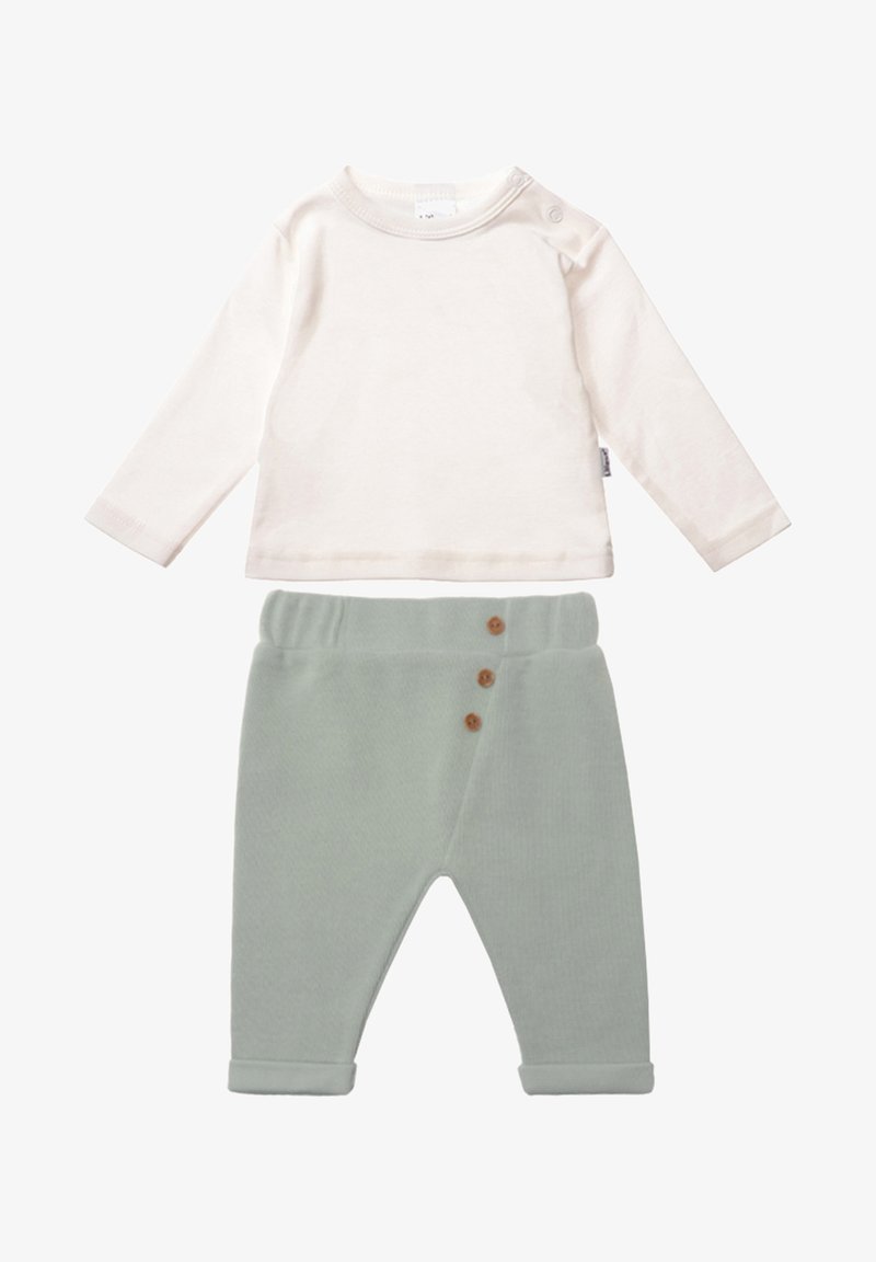 Helles Creme langärmliges Shirt mit Schulterdruckknöpfen, kombiniert mit weichen, grünen Baumwollhosen, die drei braune Knöpfe und hochgekrempelte Bündchen aufweisen.