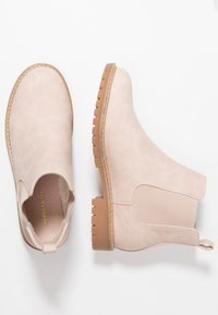 Botas de tobillo de imitación de cuero rosa con paneles laterales elásticos, acentos texturizados, punta redonda y suela baja de goma marrón.