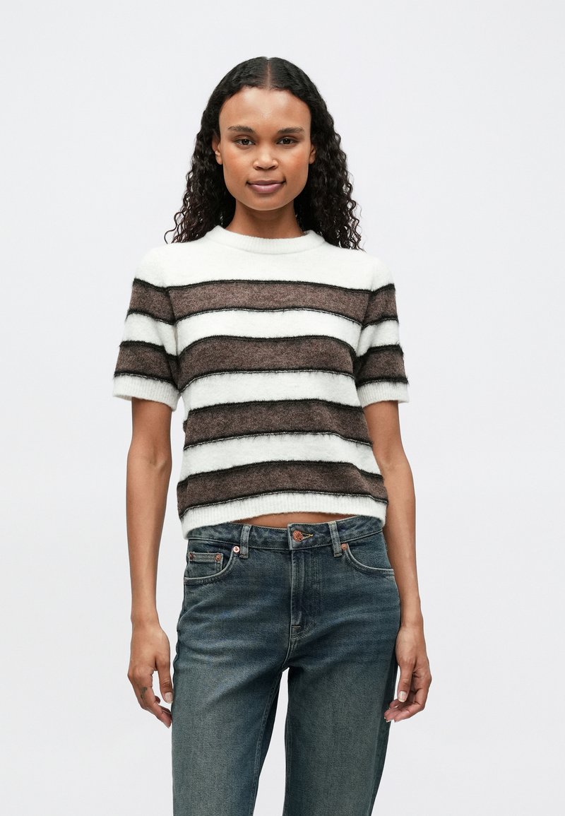 Gestreifter Strickpullover mit wechselnden braunen und weißen Streifen, kurzen Ärmeln, einem runden Ausschnitt und einem cropped Saum. Getragen mit blauen Jeans.