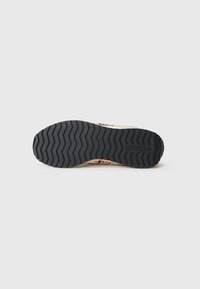 Juodas gumos padas su zigzag modeliu, viršutinėje dalyje yra kreminės ir rožinės spalvų dizainas. Reebok logotipas įspaustas pado.