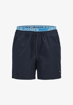 Marineblauwe zwembroek met elastische tailleband, contrasterend blauw logo label, trekkoord met blauwe en zwarte accenten, gladde textuur.