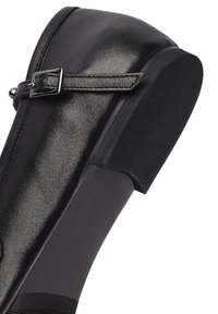 Scarpa in pelle nera con punta arrotondata, cinturino sottile e fibbia metallica, caratterizzata da una suola testurizzata nera a contrasto e un design del tacco curvo.