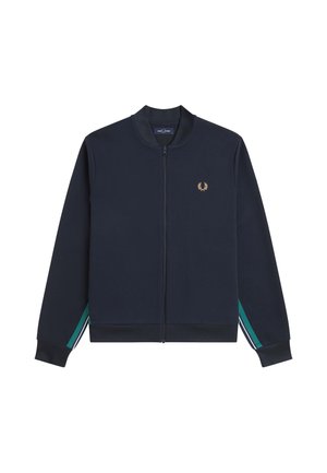 Veste zippée bleu marine avec col et poignets côtelés, petit logo de laurier doré sur la poitrine et rayures vertes et blanches sur les manches.