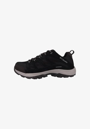 Zapato de senderismo negro impermeable con parte superior de malla y ante, entresuela gris y suela de goma texturizada, con cordones y asa.