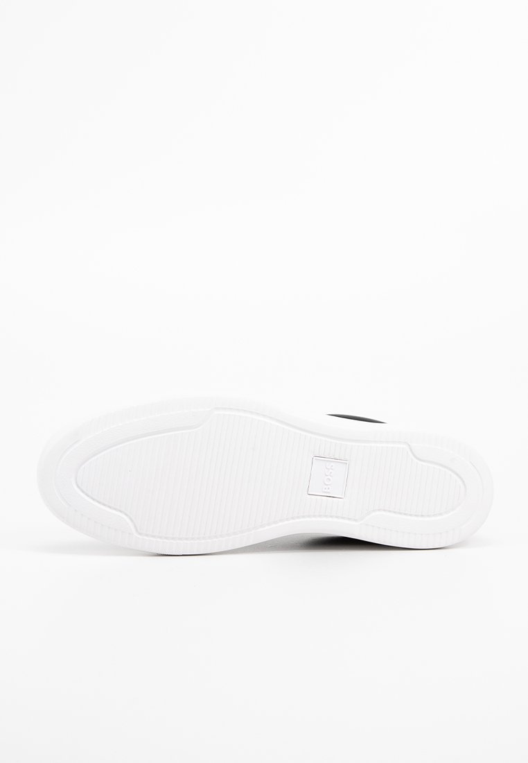 Suola di sneakers bianche con texture rigata, motivo circolare nella parte del tallone e logo centrale in un riquadro rettangolare. Superficie liscia con dettagli minimi.