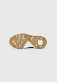 Brown rubber sole with deep, triangular tread patterns and a circular white section near the heel on a sports shoe.