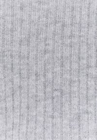 Weiches graues Strickmaterial mit einer gerippten Textur und vertikalen Streifen. Das Material wirkt leicht und leicht flauschig.