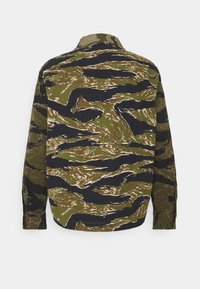Long-sleeve shirt in green and black camouflage pattern, featuring a button-down collar and textured fabric. Back view shows distinct design elements.