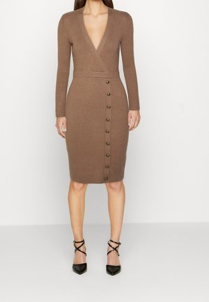 Robe en maille côtelée marron longueur genou, manches longues, encolure profonde en V et boutons verticaux, associée à des talons noirs à bout pointu avec bride à la cheville.