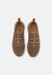 Bruna slip-on sneakers med meshuvud, elastiska snören, ögla för att dra i dem och en vadderad vit sula. Texturerad yta med subtila mönster.