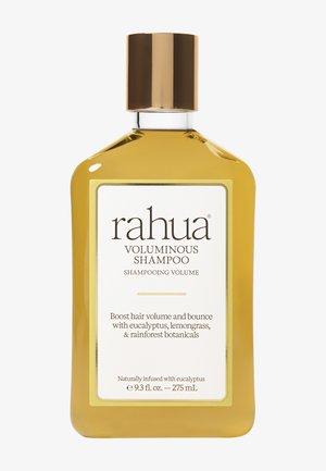 Hvælvet shampooflaske i ravfarvet med en guld hætte, der har en hvid etiket. Teksten fremhæver "Voluminerende Shampoo," beriget med eukalyptus og botaniske ingredienser.