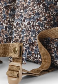 Tygväska med ett blommönster i blått, persika och brunt, med strukturerade beige remmar och en plastspänne.