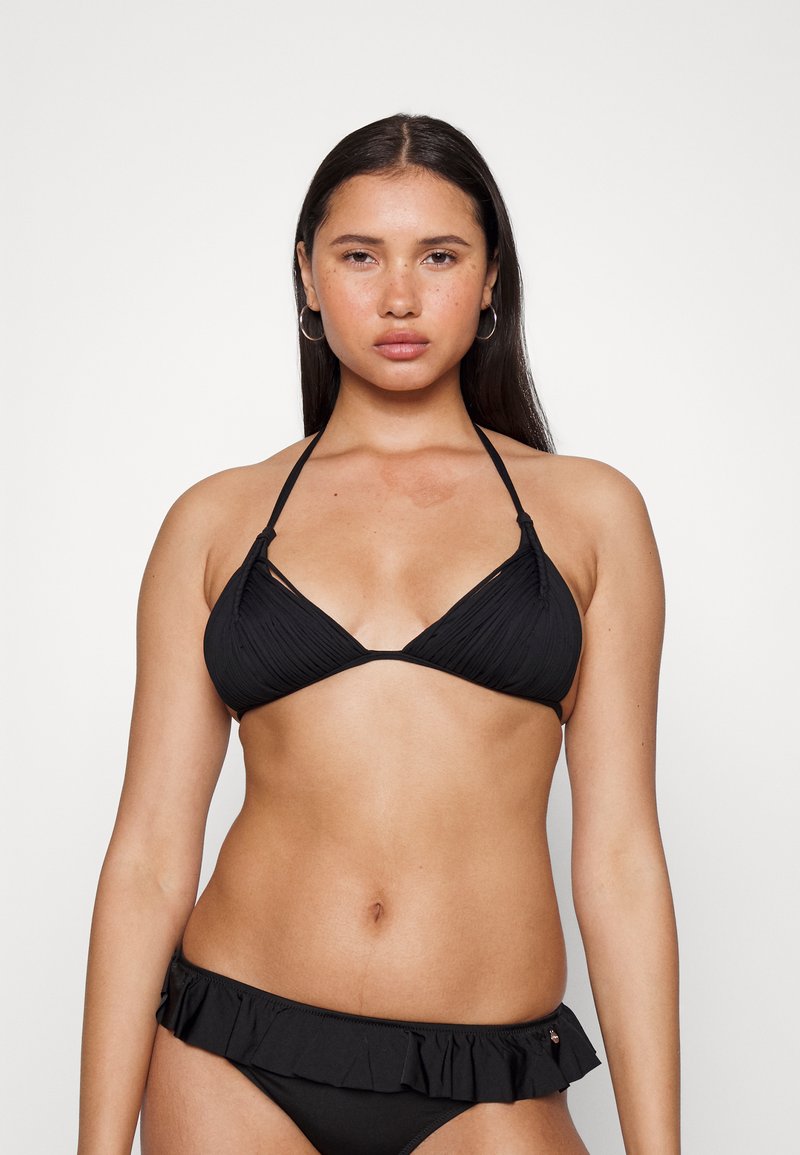 Melnā bikini komplekts, kurā ir teksturēts trīsstūrveida tops ar kakla saitēm un ruffled apakšdaļa, abi izgatavoti no gludas auduma.