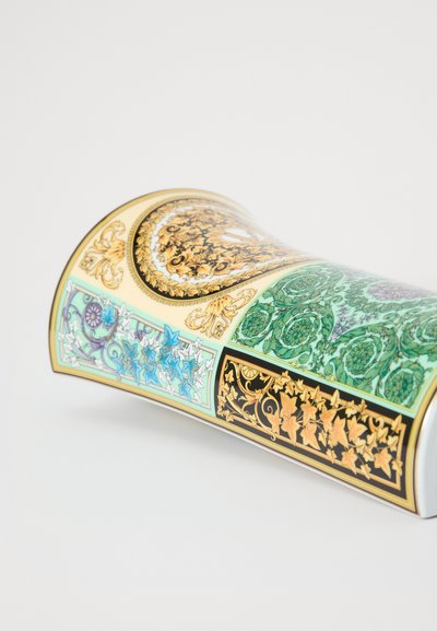 Chávena decorativa de porcelana com padrões intrincados em dourado, verde e azul sobre um fundo branco, apresentando uma forma curva e elegante.