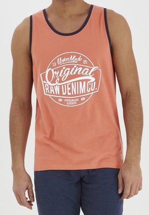 Oranges Tanktop mit dunkelblauem Saum, ausgestattet mit einem weißen kreisförmigen Grafik, die in fetter Schrift "Original Raw Denim Co." liest. Weicher Stoff.