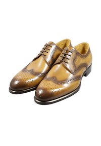 Scarpe brogue in pelle marrone con perforazioni decorative, una forma elegante e una finitura lucida. Presentano lacci e una suola a contrasto.