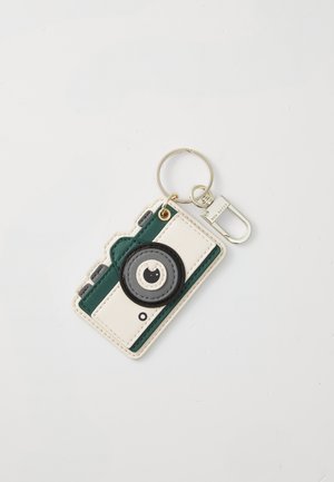 Keychain designed as a camera, featuring a white and green exterior, round black lens detail, circular hardware, and a metal keyring attachment.
