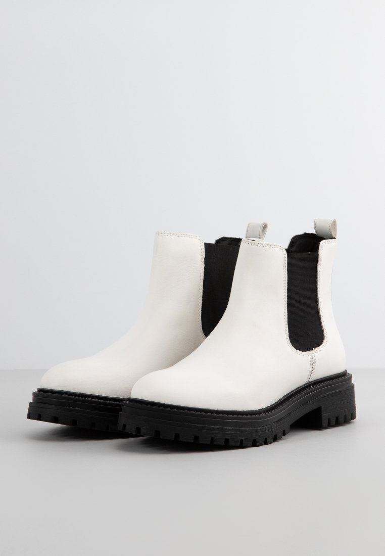 Stivaletti Chelsea in pelle bianca con pannelli elasticizzati neri, con linguette di estrazione e suole in gomma nera chunky con texture scanalata.